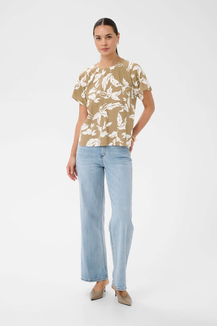 Femme portant la Blouse Marlo fluide à imprimé feuillage avec manches courtes, parfait pour un look estival élégant et confortable.