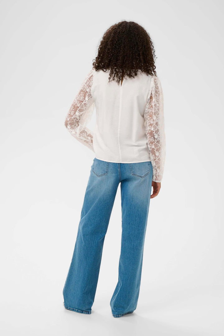 Vue arrière de la Blouse avec broderie, manches longues en dentelle, portée avec un jean.