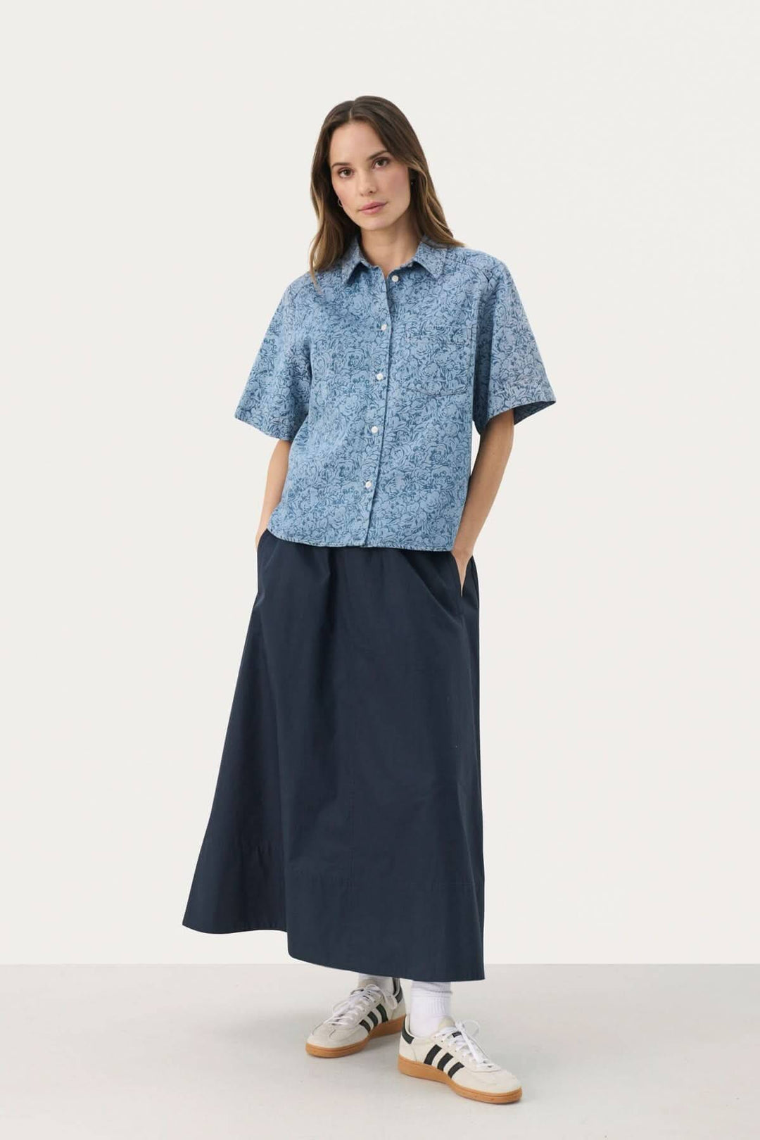 Femme portant une blouse en jeans Nicla avec une jupe longue, affichant un style décontracté et polyvalent.
