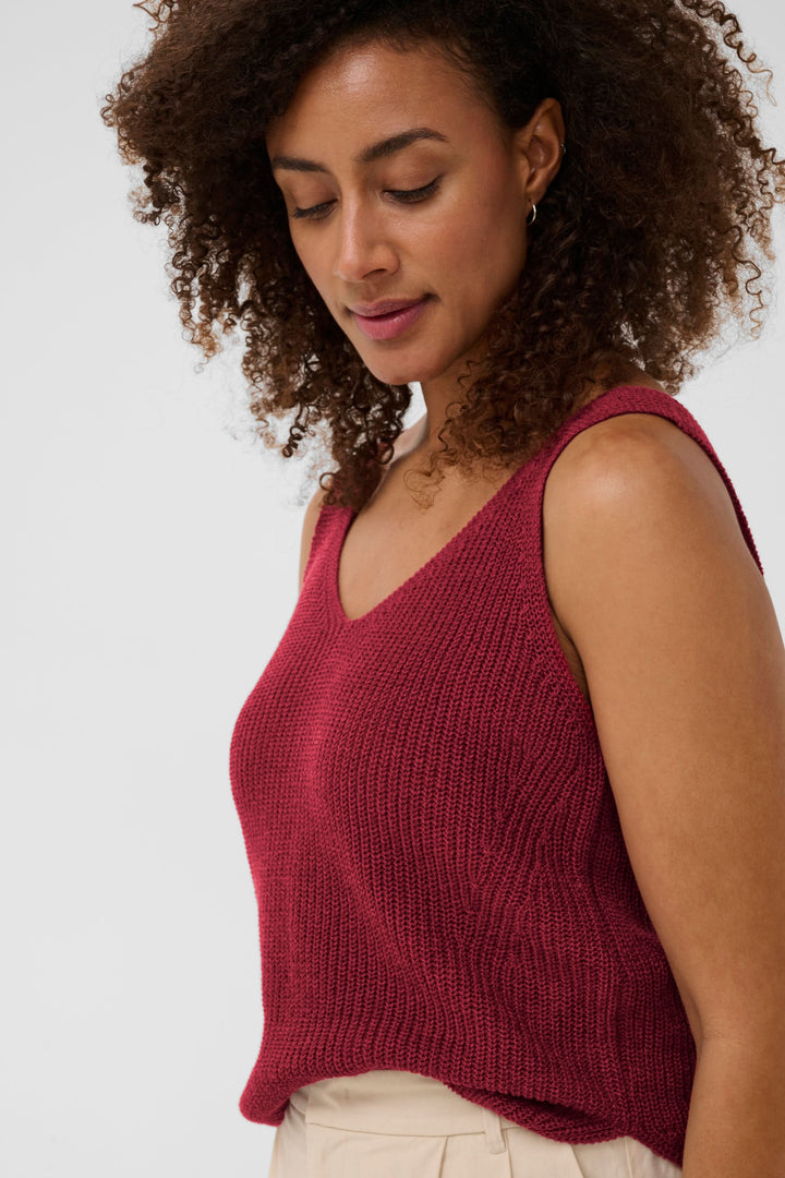 Femme portant la Camisole Rebecca tricotée col v sans manches en maille texturée rouge, idéale pour un look naturel et décontracté.