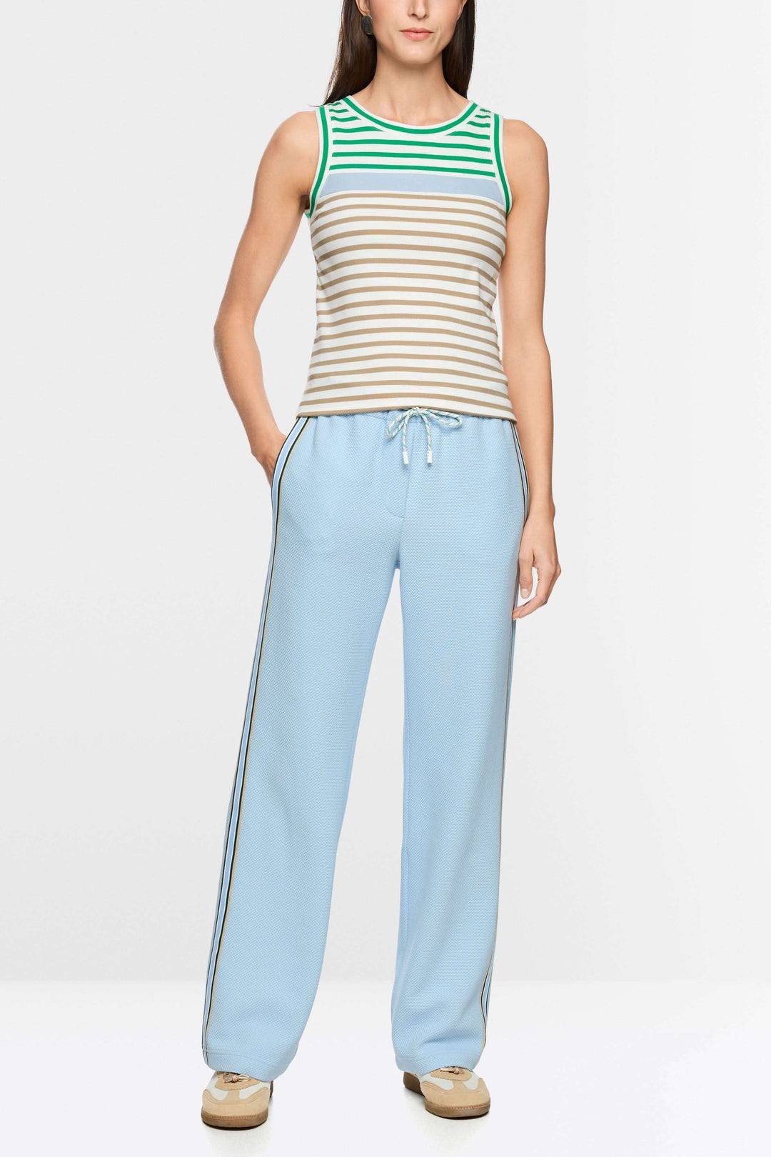Femme portant une camisole rayé en coton avec encolure ronde contrastante, associée à un pantalon bleu ciel pour un look décontracté.