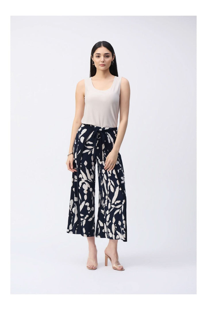 Femme portant une camisole soyeuse à col rond et un pantalon large imprimé, avec des talons beiges, style élégant et décontracté.