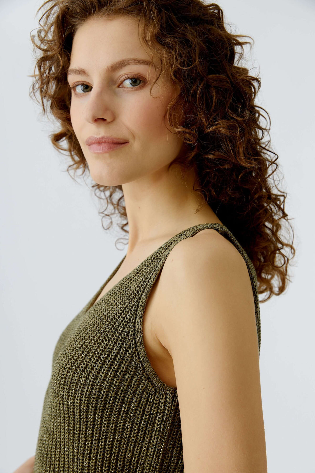 Femme portant une camisole tricoté en fil spécial olive avec encolure en V et maille texturée, silhouette simple et actuelle.