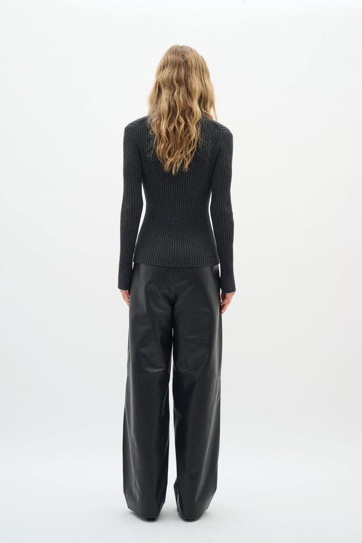 Vue arrière du Cardigan Gia en maille côtelée noire, porté avec un pantalon ample, touche élégante et féminine.