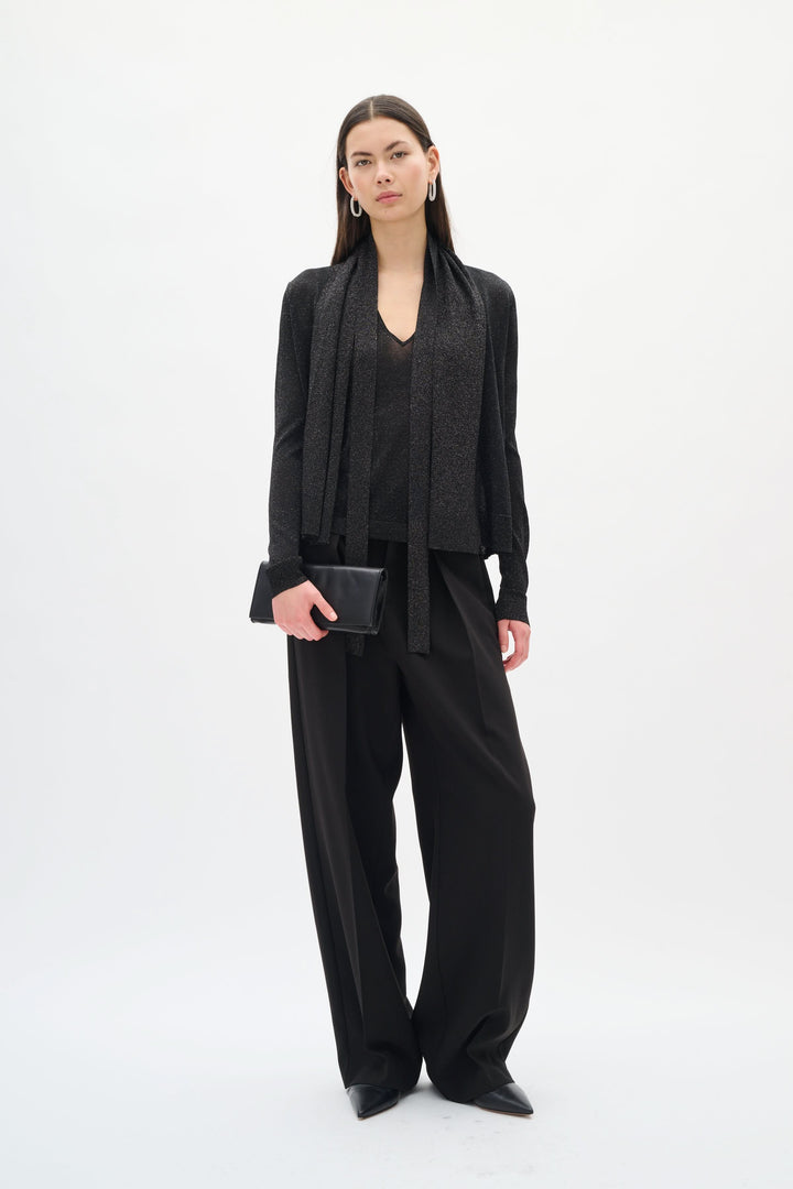 Modèle portant le Cardigan Thani à effet scintillant avec foulard intégré, rehaussant une tenue élégante et sophistiquée.
