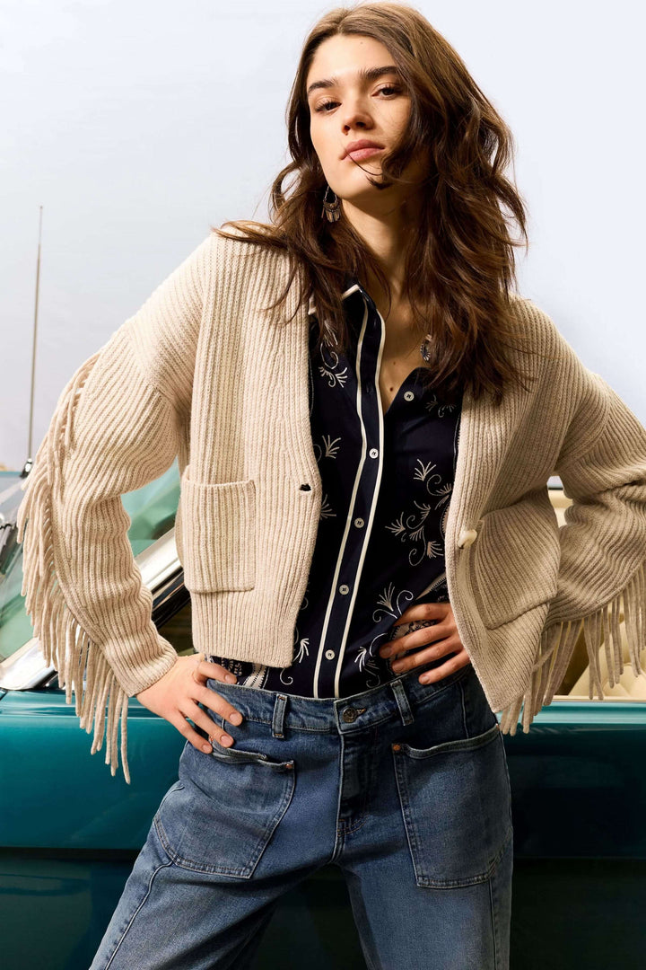 Femme portant un Cardigan avec franges, ample et confortable, en coton et laine, avec manches à franges et décolleté en V.