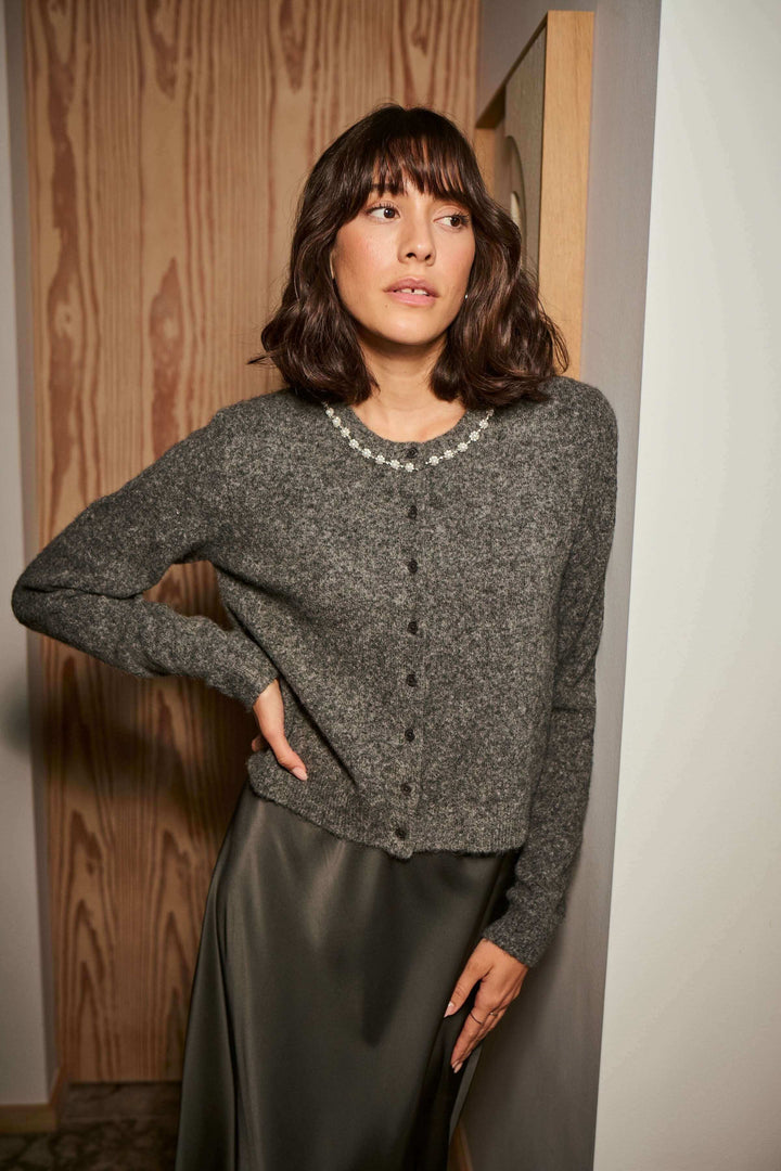 Femme portant un cardigan en laine bouclée à col orné, ajoutant une touche élégante à sa tenue avec ce design raffiné et lumineux.