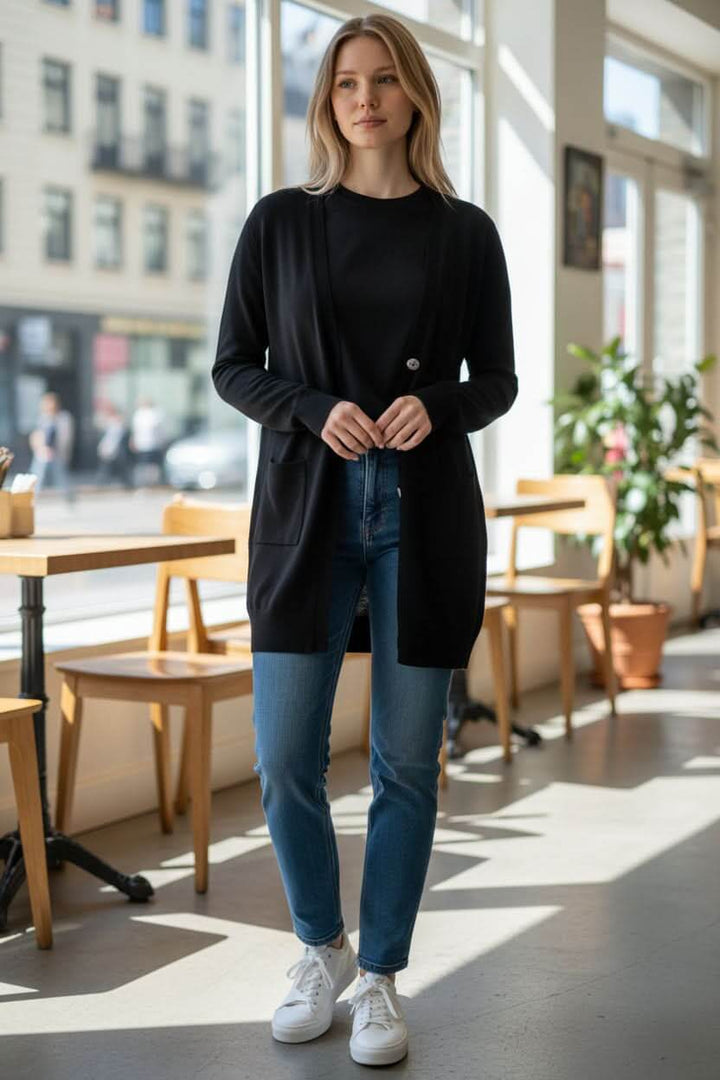 Femme portant un Cardigan long boutonné Miko noir, col V et coupe droite, dans un café lumineux.