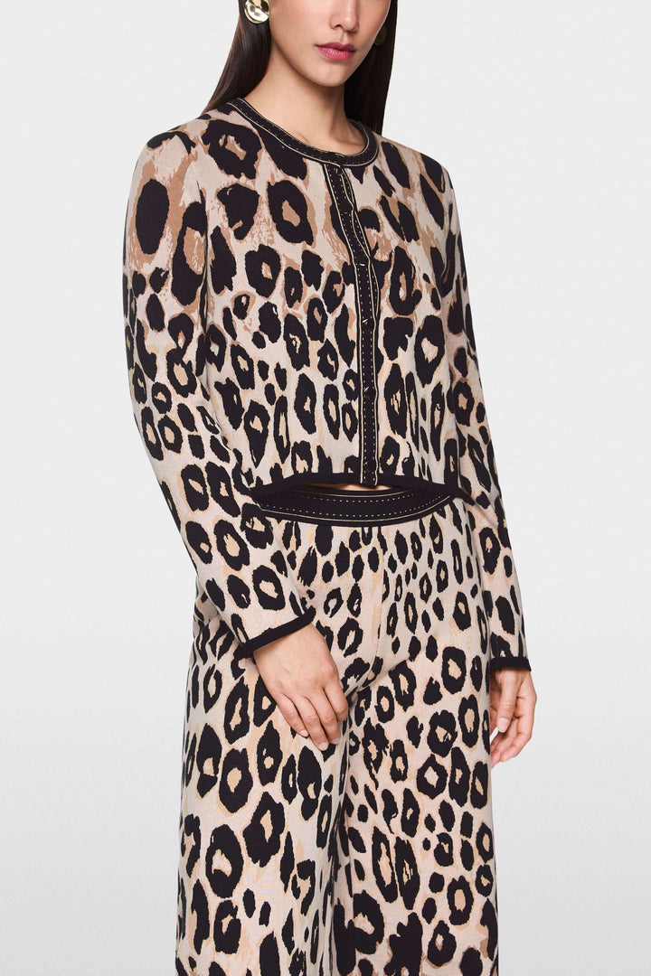Femme portant un cardigan léopard à motif animal, coupe droite et finitions contrastées, une tenue audacieuse et moderne.