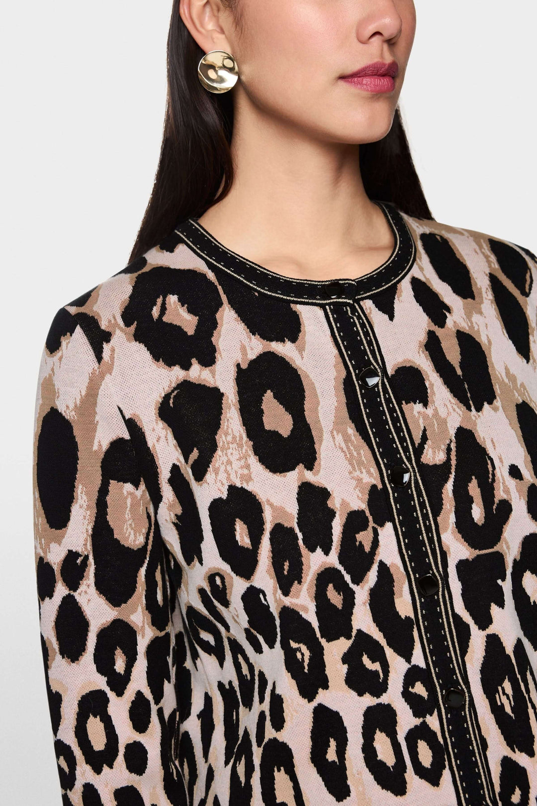 Femme portant un cardigan léopard à motif animal avec finitions contrastées, coupe droite élégante et look moderne audacieux.