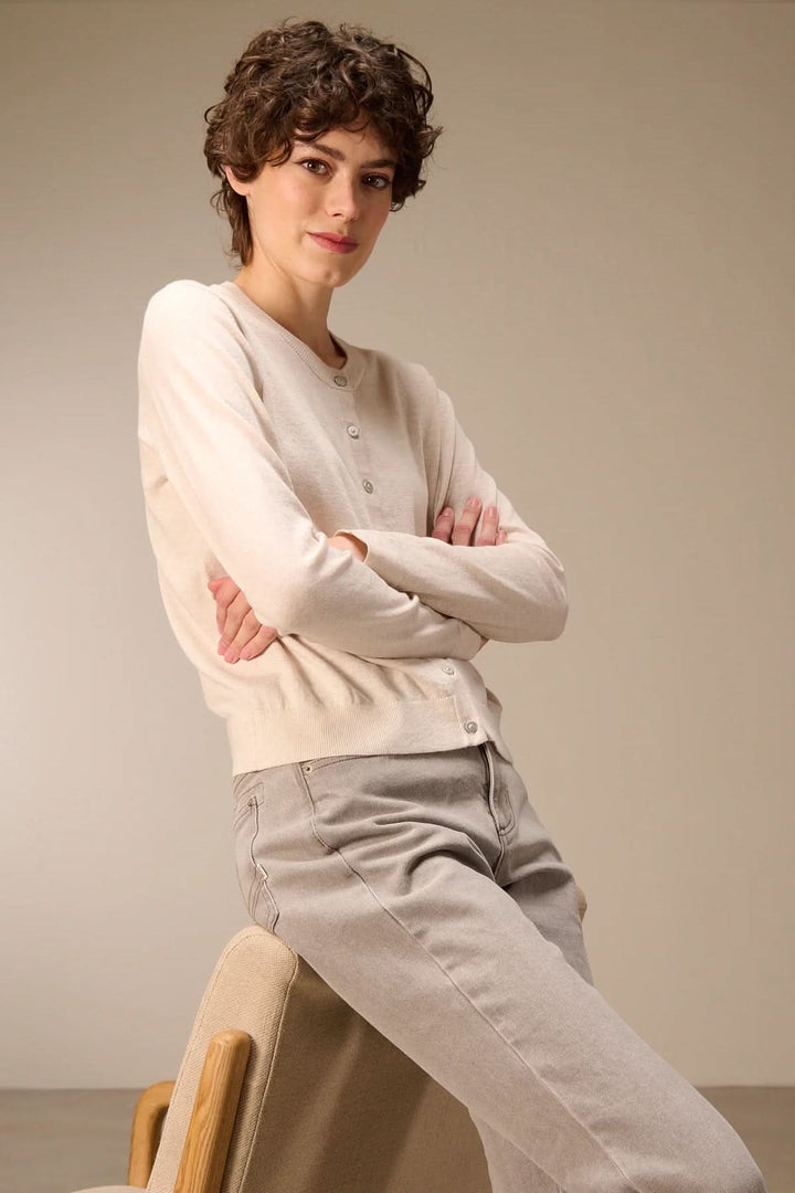 Cardigan tricot fin boutonné col rond porté par une femme posant élégamment, manches longues et coupe ajustée, style décontracté et raffiné