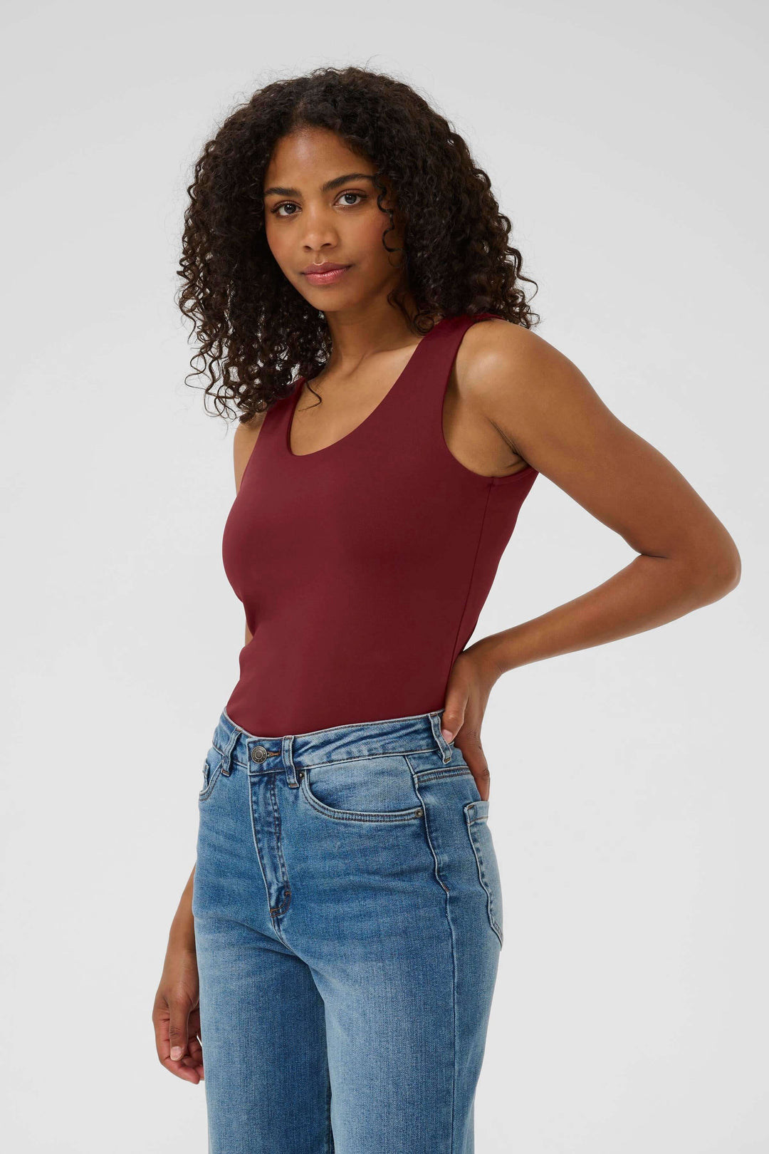 Femme portant un débardeur bordeaux avec jean, look casual élégant