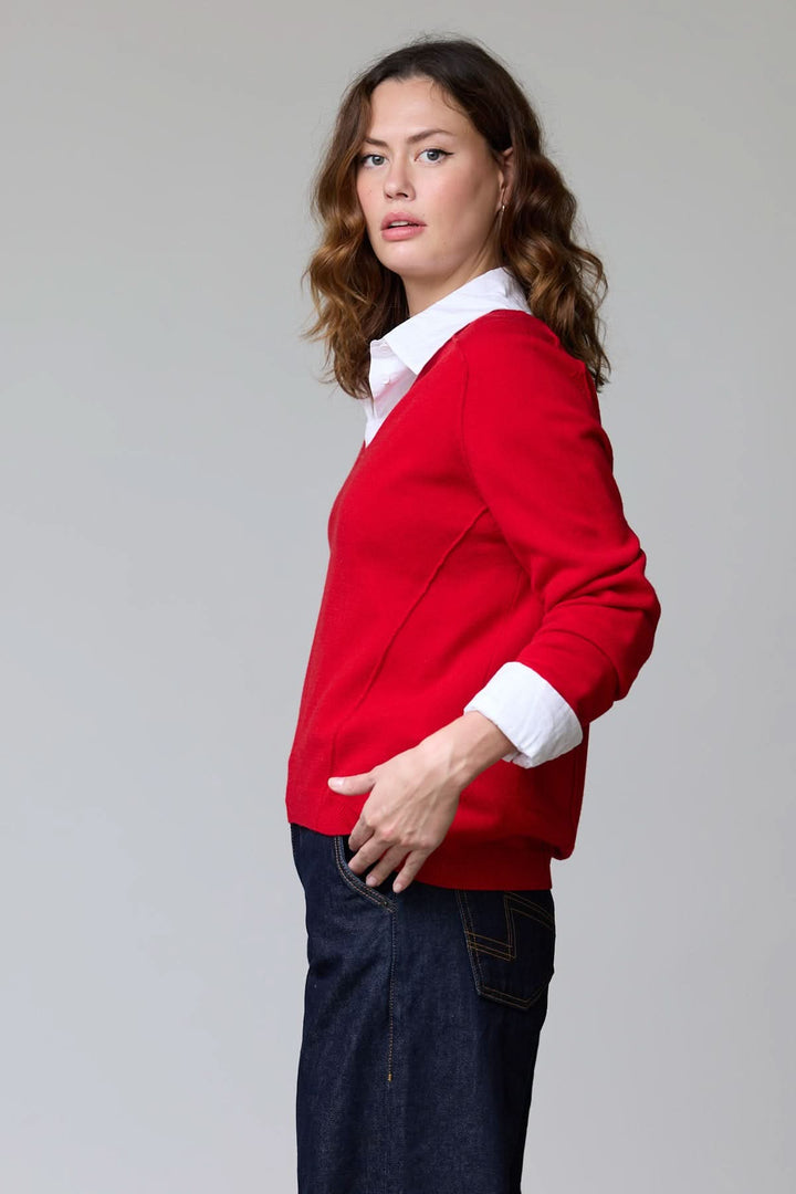 Chandail col en V classique en maille douce, porté par une femme sur une chemise blanche, offrant un look élégant et polyvalent.