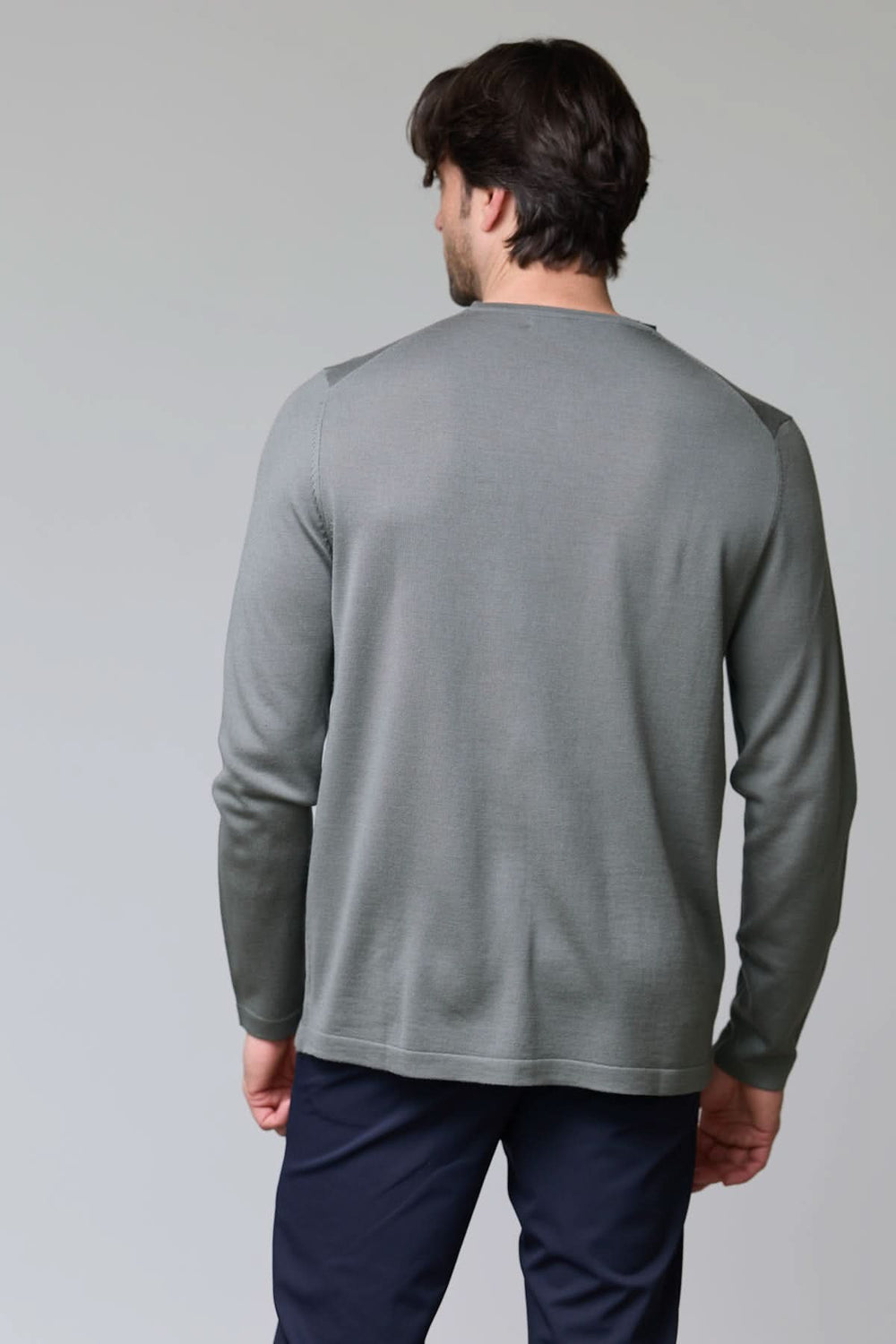 Homme portant un chandail col rond en tricot fin gris, vue de dos, montrant la maille douce et coupe ajustée. Décris moi le produit en français.
