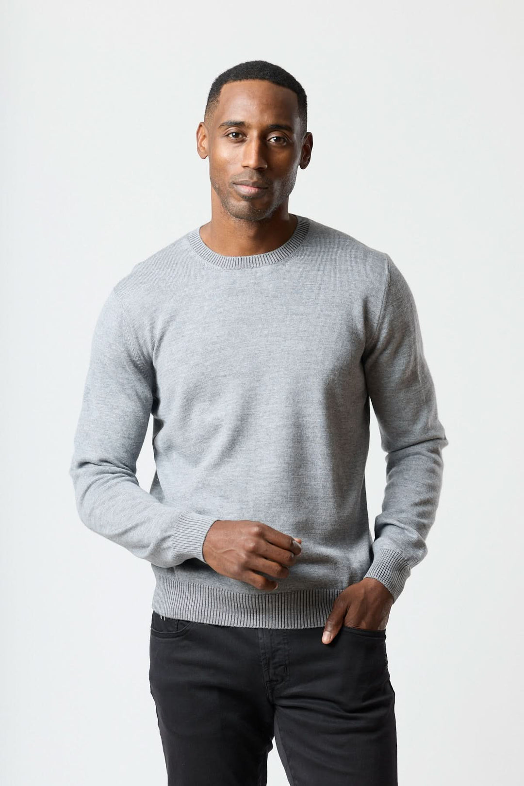 Homme portant un chandail col rond essentiel gris, coupe régulière et finitions côtelées, offrant confort quotidien et style moderne.