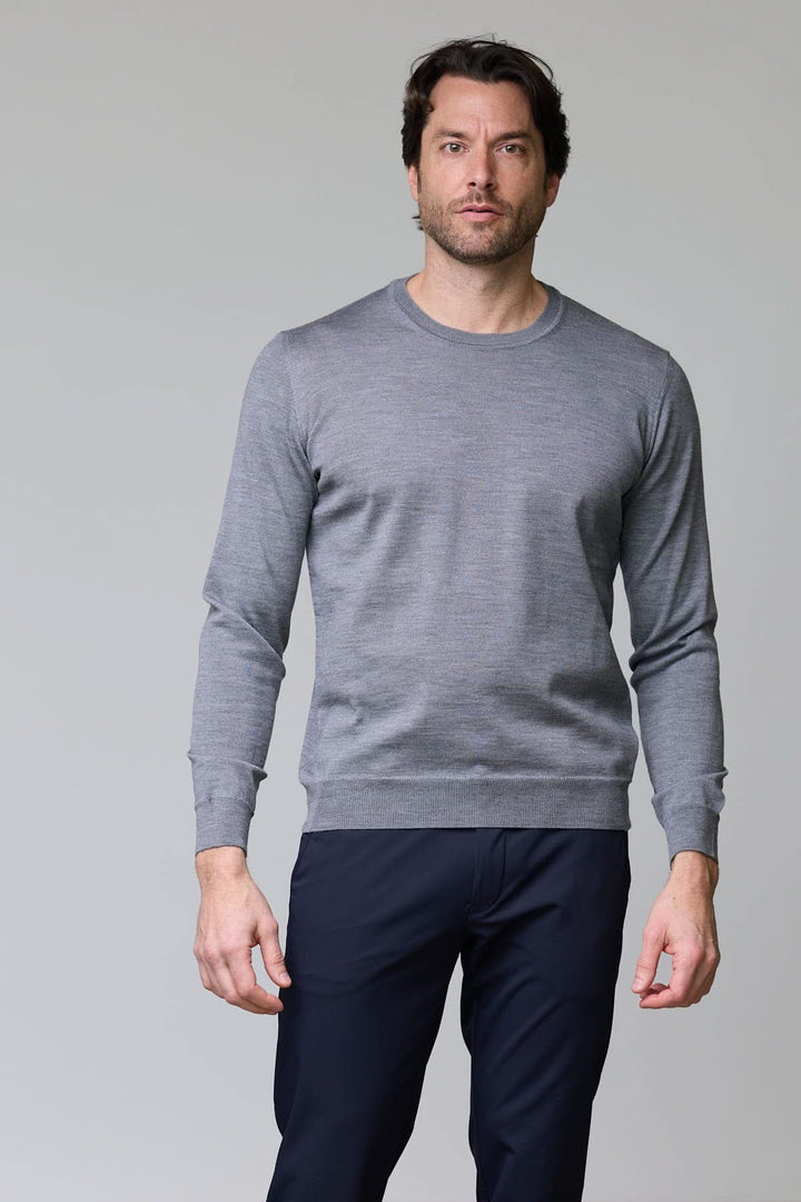 Homme en chandail en laine mérinos gris avec col rond, manches longues et coupe moderne, idéal pour une allure élégante et décontractée.