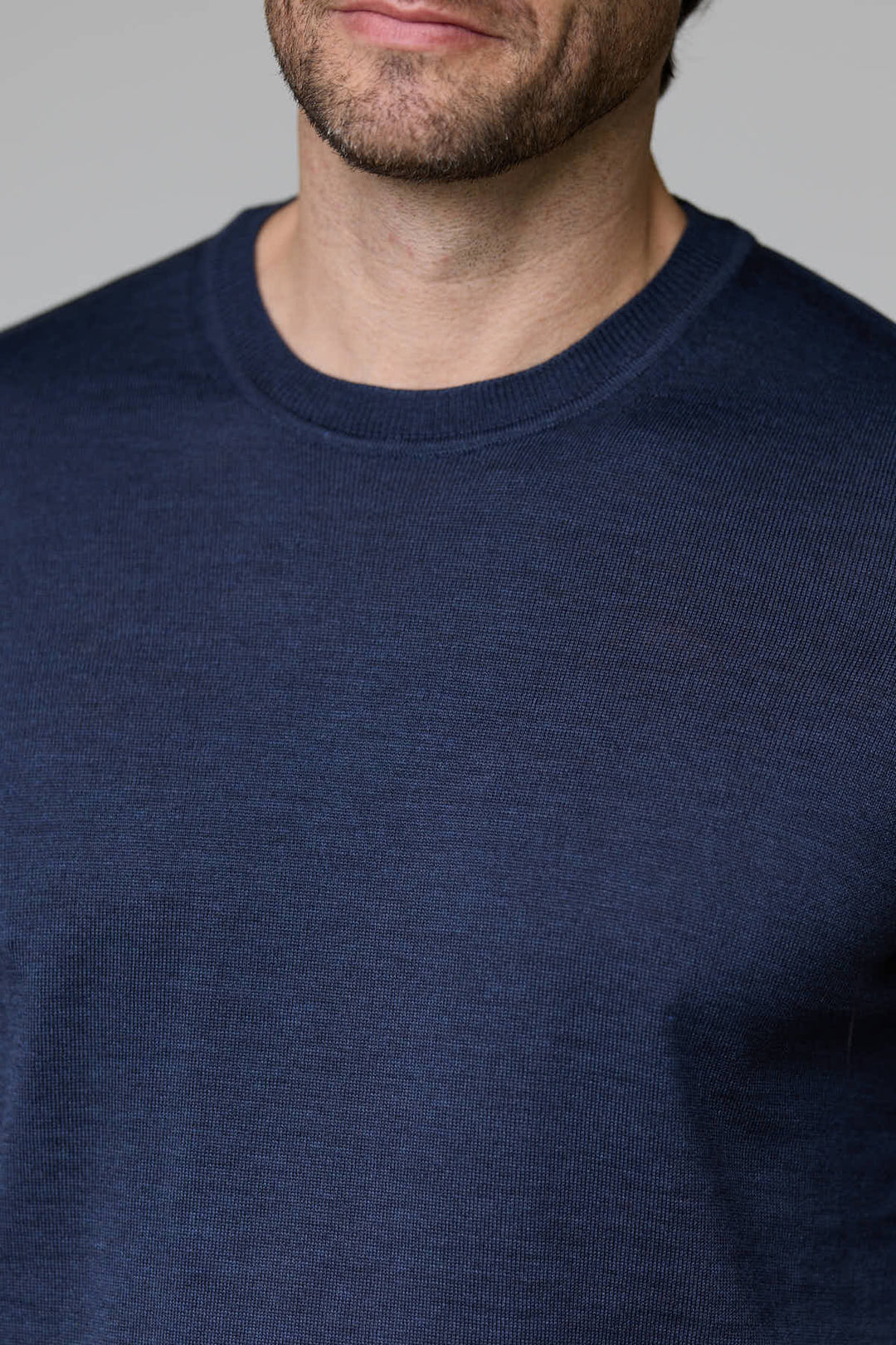 Homme portant un chandail bleu foncé à col rond en laine mérinos légère pour un confort optimal.
