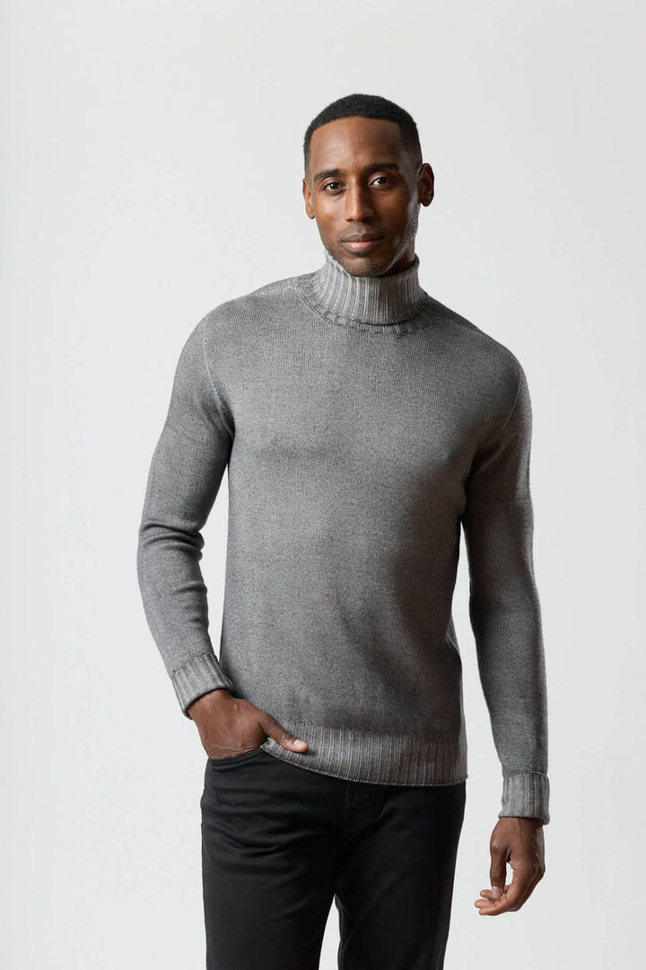 Homme portant un chandail col roulé jauge fine gris, style moderne et épuré, parfait avec un veston ou manteau.