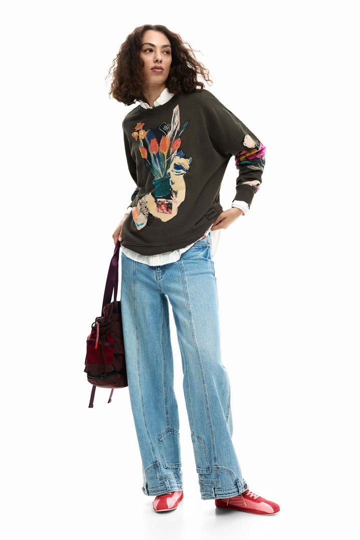 Femme portant un chandail collage dessin artistique avec jeans, idéal pour un style décontracté et créatif.