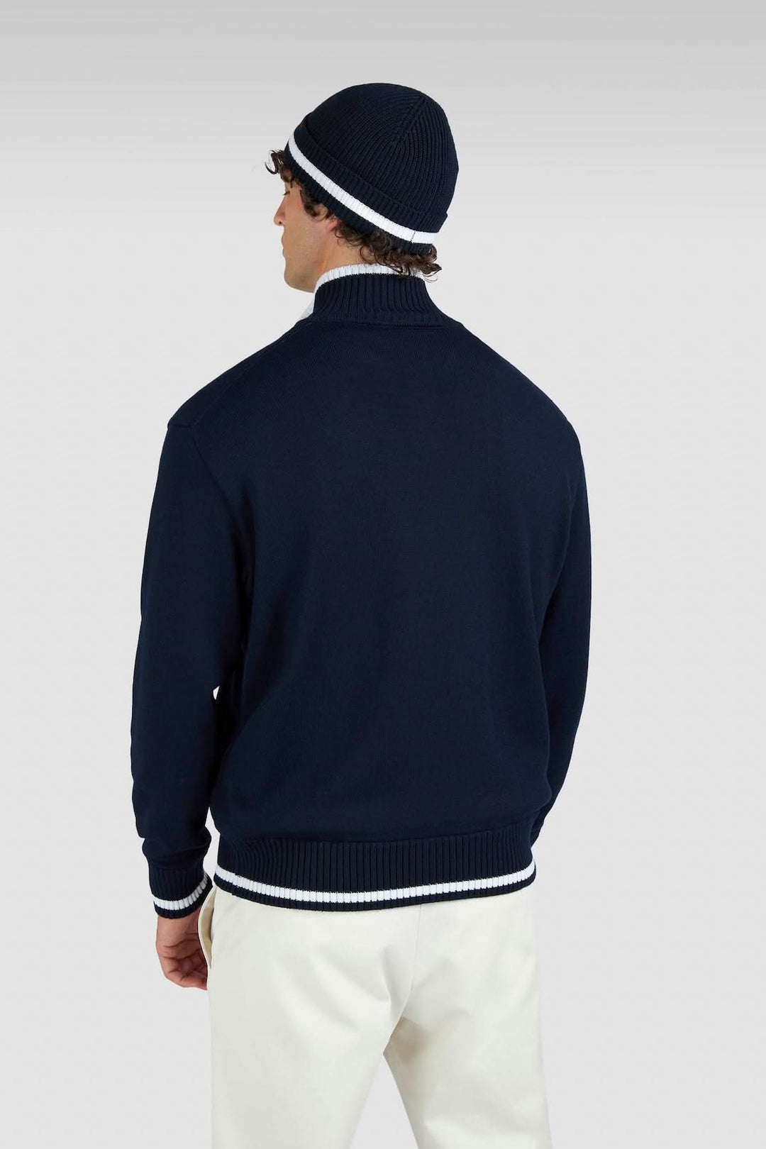 Homme portant un chandail à demi-fermeture bleu marine avec détails contrastés, style décontracté-chic.