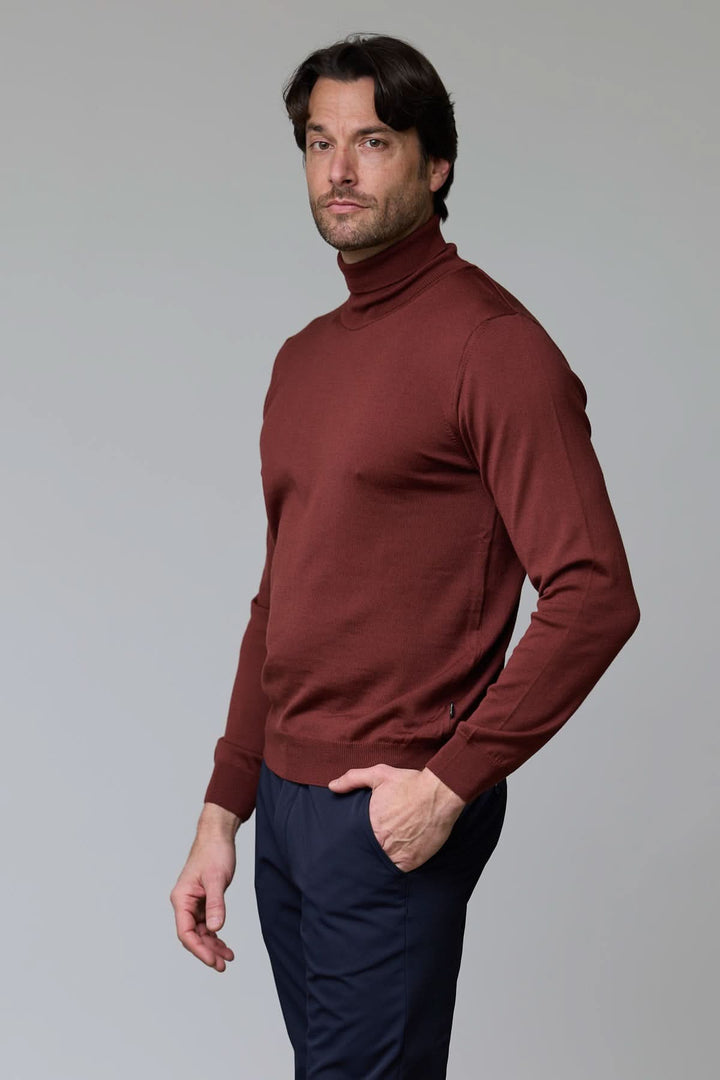 Homme portant un chandail en laine mérinos fine marron avec col roulé et coupe ajustée, style élégant et intemporel.