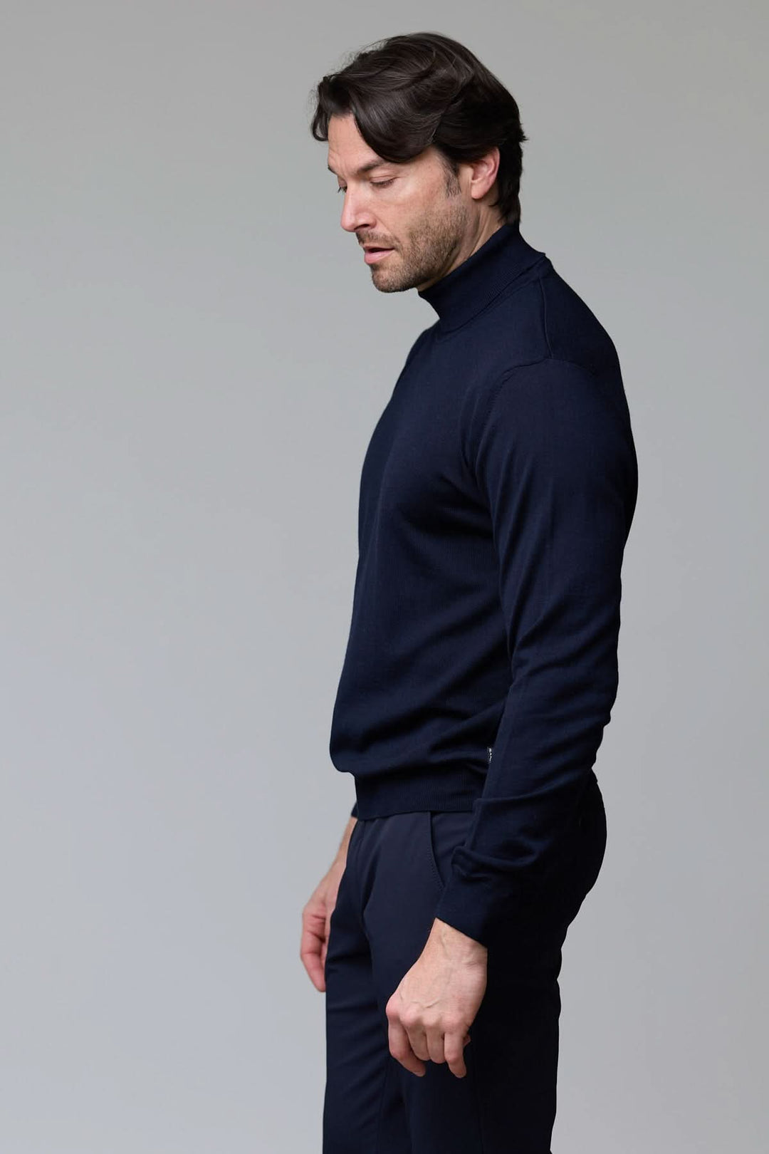 Homme portant un chandail en laine mérinos fine bleu marine avec col rond et bordure côtelée, style élégant et intemporel.
