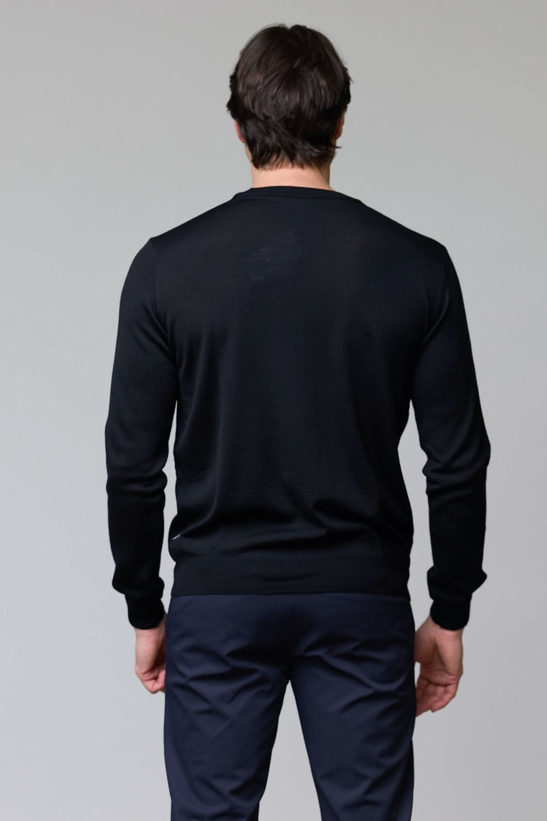 Homme portant un chandail en laine mérinos fine avec col rond, noir, vue de dos.