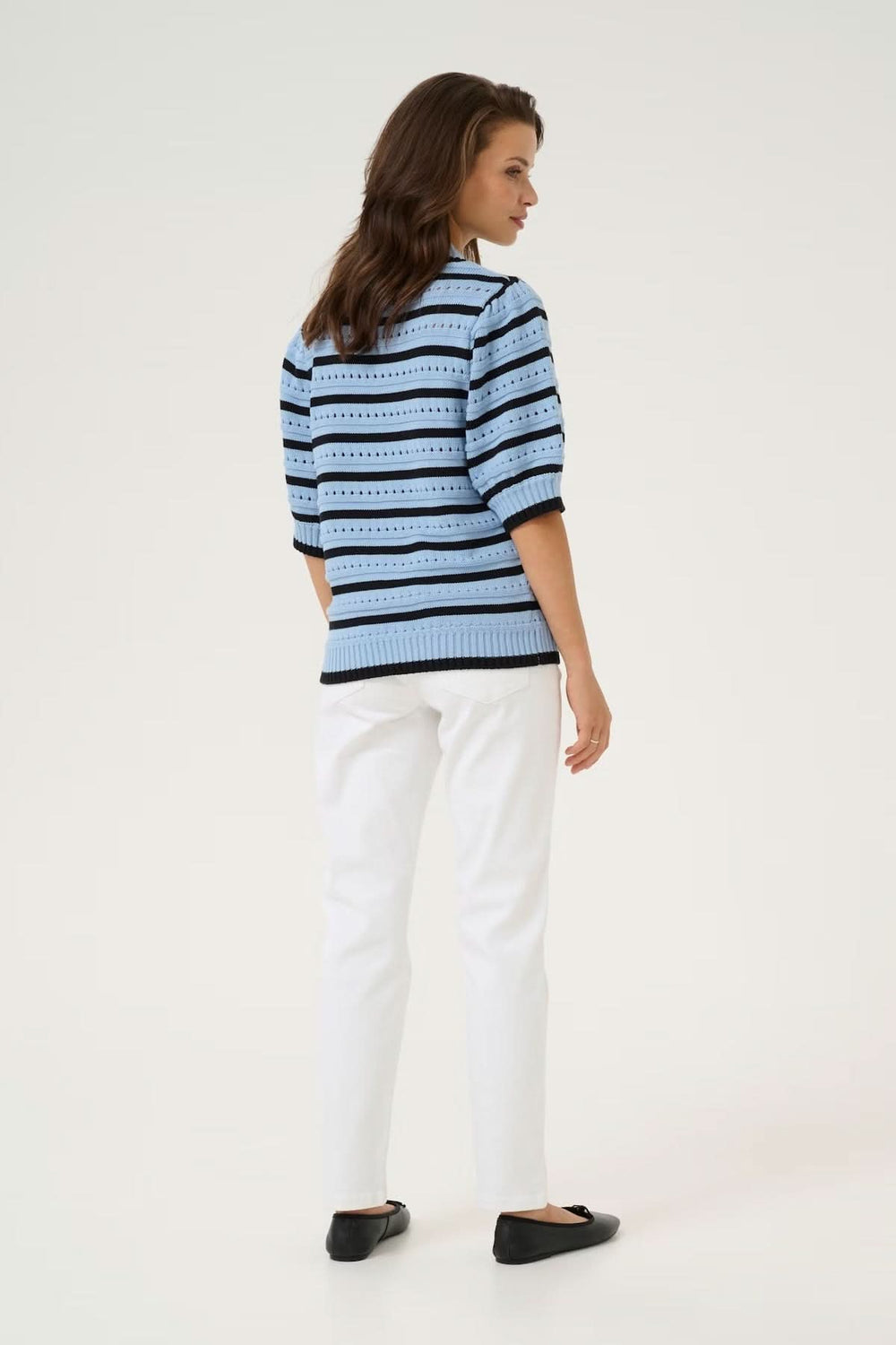 Chandail en maille ajourée rayé bicolore, vue arrière, associé à un pantalon blanc décontracté.