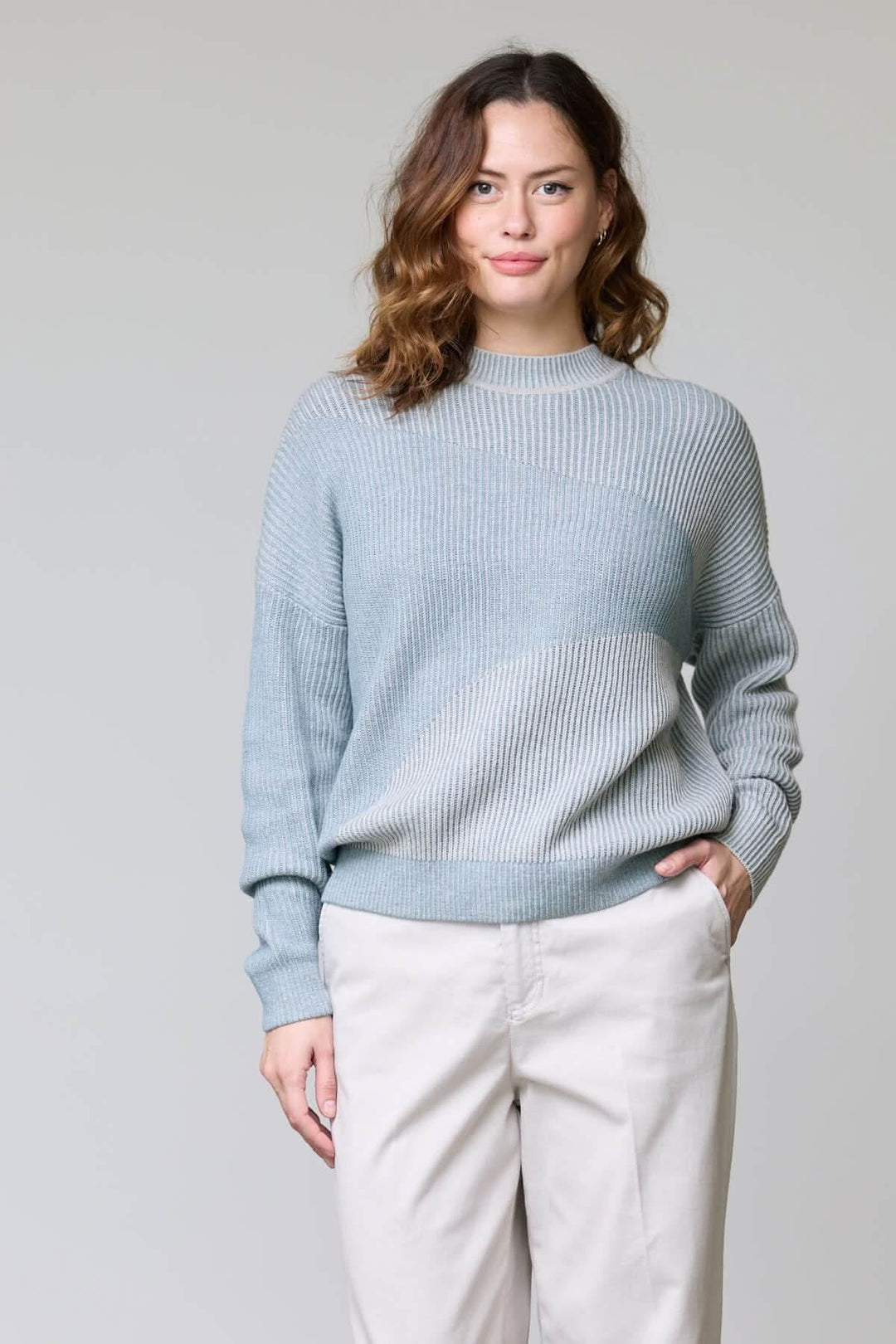 Chandail en tricot côtelé gris clair avec encolure ronde et coupe décontractée porté par une femme, idéal pour une tenue moderne.