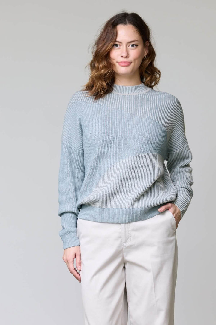 Chandail en tricot côtelé gris clair avec encolure ronde et coupe décontractée porté par une femme, idéal pour une tenue moderne.