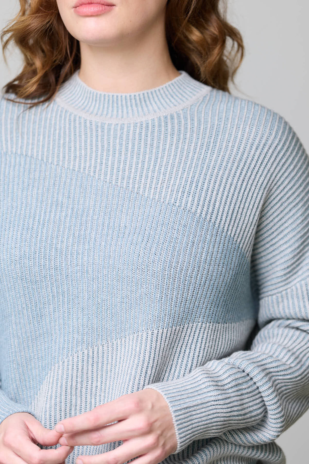 Chandail en tricot côtelé bleu avec encolure ronde et manches longues pour une tenue confortable et moderne.
