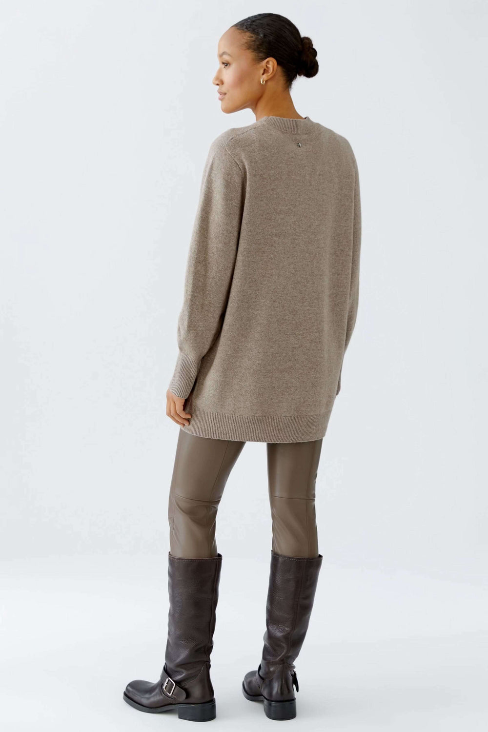 Femme portant un chandail long à col rond avec manches longues, style minimaliste et confortable, parfait avec un legging ou pantalon ajusté.