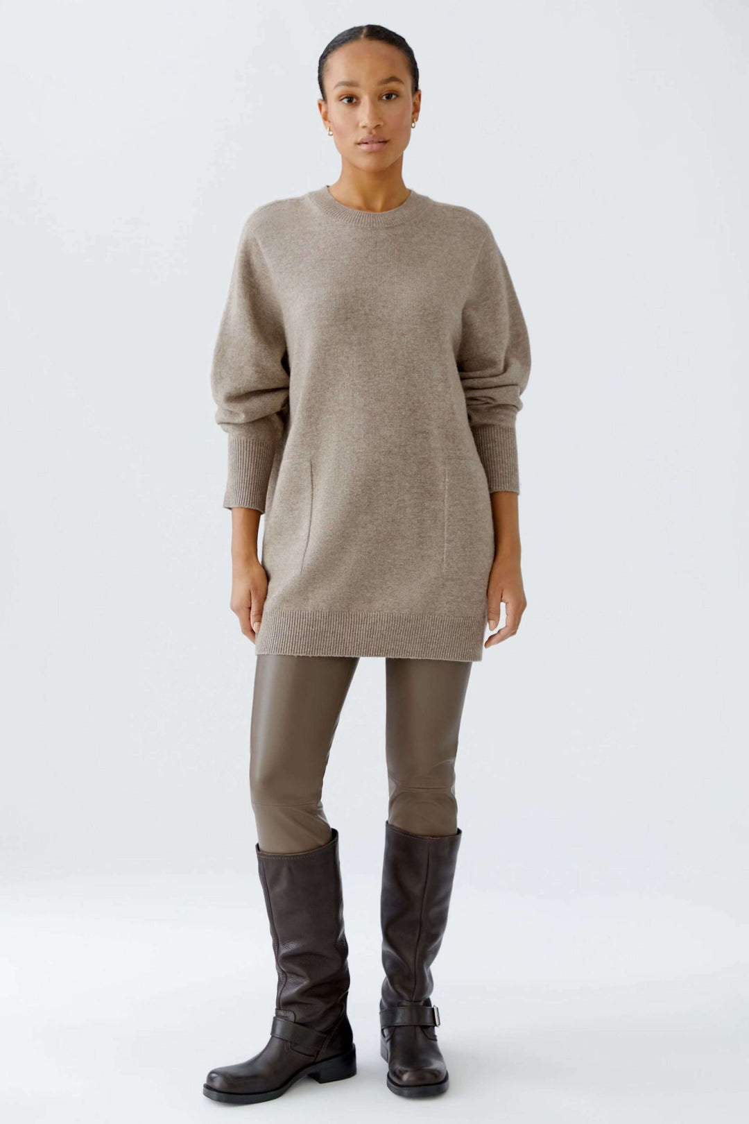 Chandail long à col rond en maille douce, coupe ample, manches longues, porté avec un legging et des bottes pour un style minimaliste.
