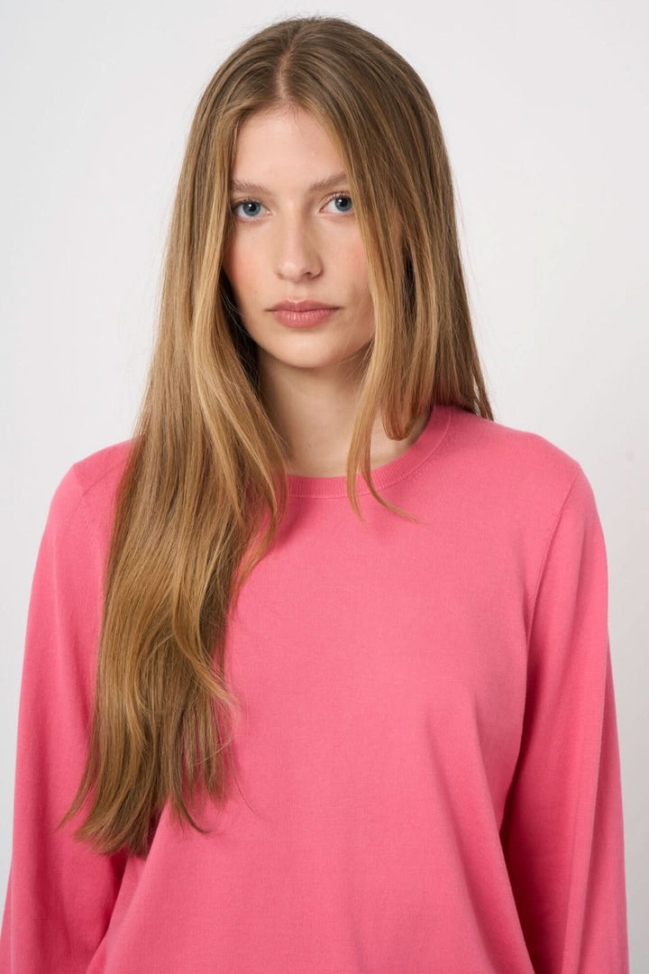 Femme portant un chandail à manches longues rose avec une coupe droite, encolure ronde et tissu doux, idéal pour le quotidien.