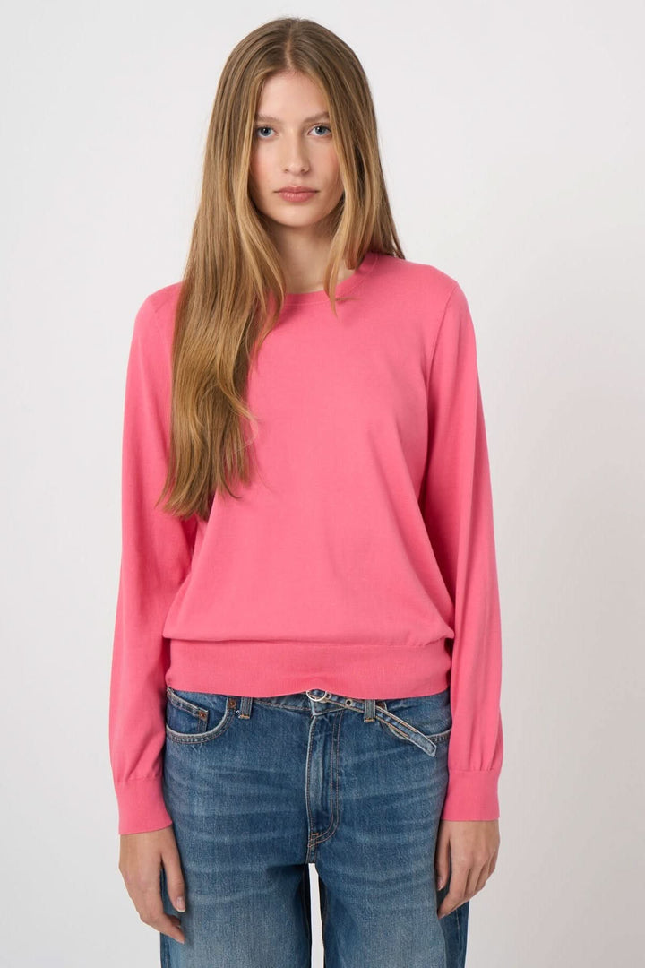 Femme portant un chandail à manches longues rose avec une coupe droite et confortable, encolure ronde, sur un fond neutre.