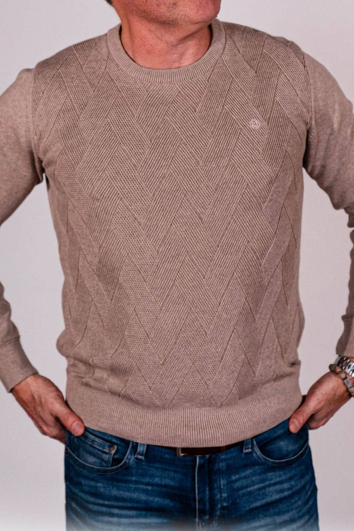 Chandail beige avec motif chevron, col rond, porté par un homme, associé à un jean. Élégant et confortable.