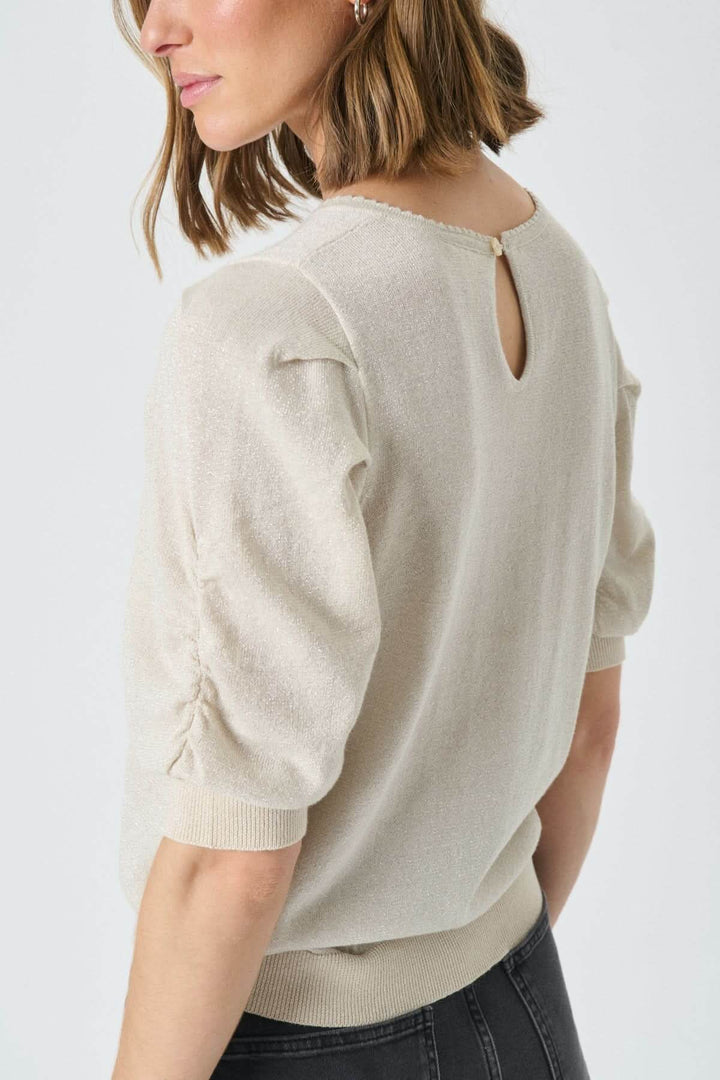 Femme portant un Chandail scintillant Varaia avec manches courtes et encolure ronde, texture délicatement brillante pour look élégant.