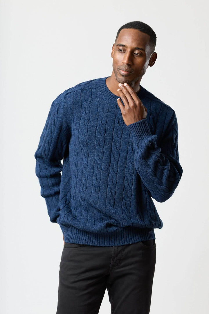 Chandail torsadé col rond en maille bleue avec texture câblée, porté par un homme, parfait pour un style quotidien confortable.