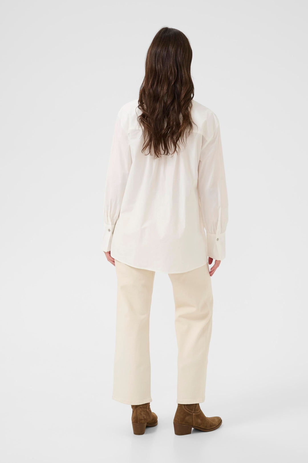 Vue arrière de la Chemise Alison blanche, élégante et fluide, associée à un pantalon beige et des bottines marron.