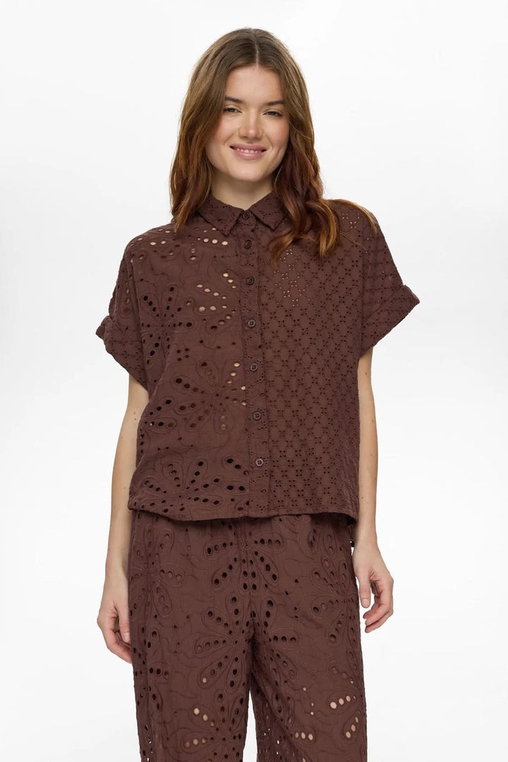 Femme portant une chemise brodée anglaise à manches courtes marron, style décontracté et élégant, idéale pour l&