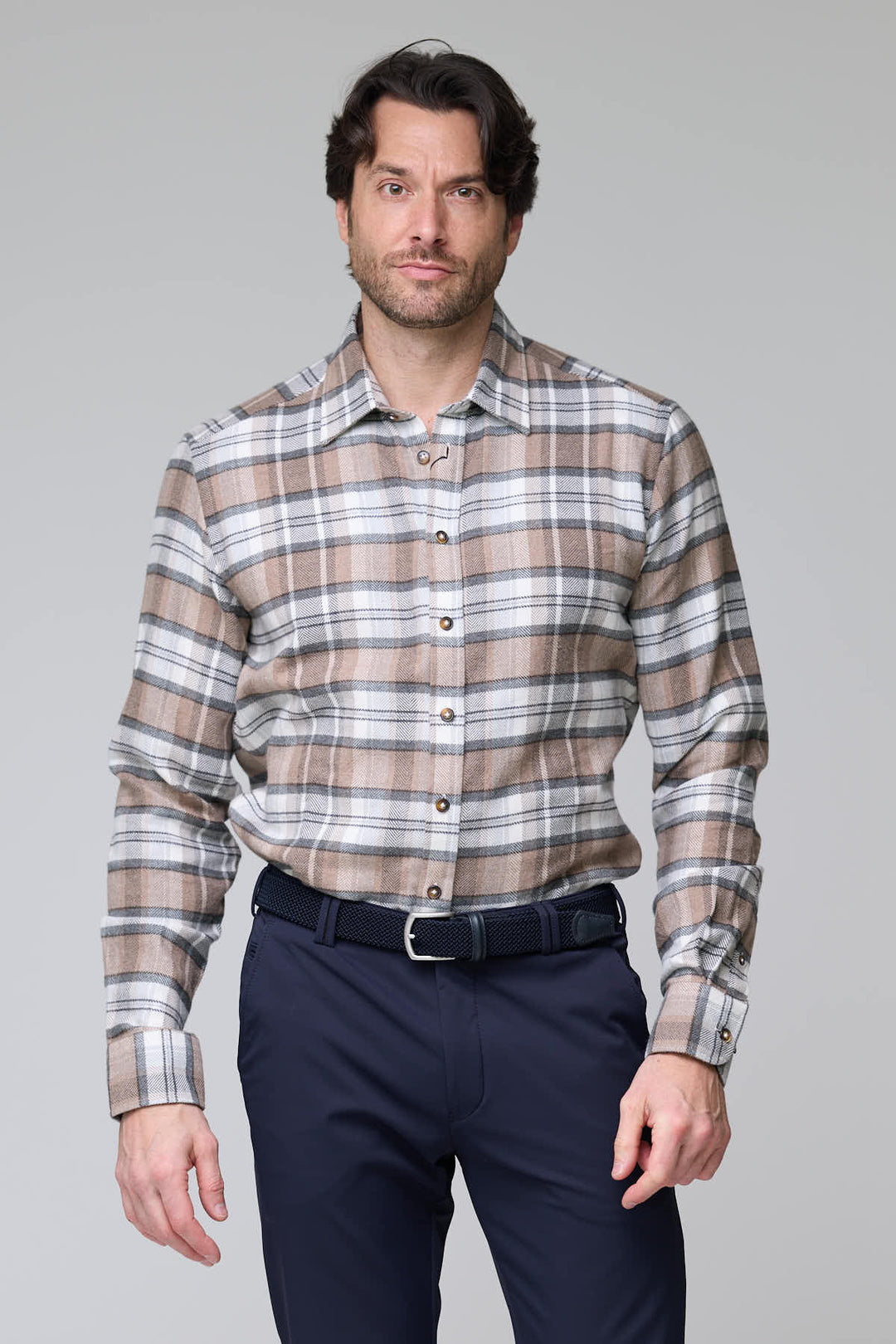 Homme portant une chemise à carreaux chevrons beige et gris en flanelle douce avec un pantalon bleu marine.