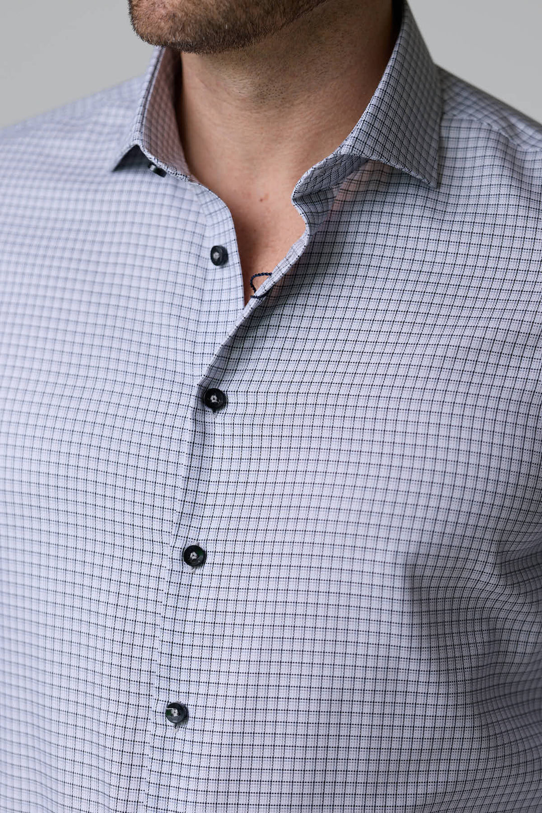 Homme portant une chemise à carreaux fins à manches longues, coupe ajustée, pour un look professionnel et décontracté.