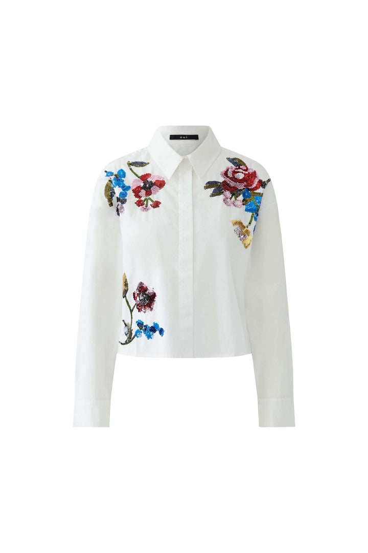 Chemise coupe moderne avec broderies florales, silhouette artistique et féminine. Élégance et modernité pour un look soigné ou décontracté.