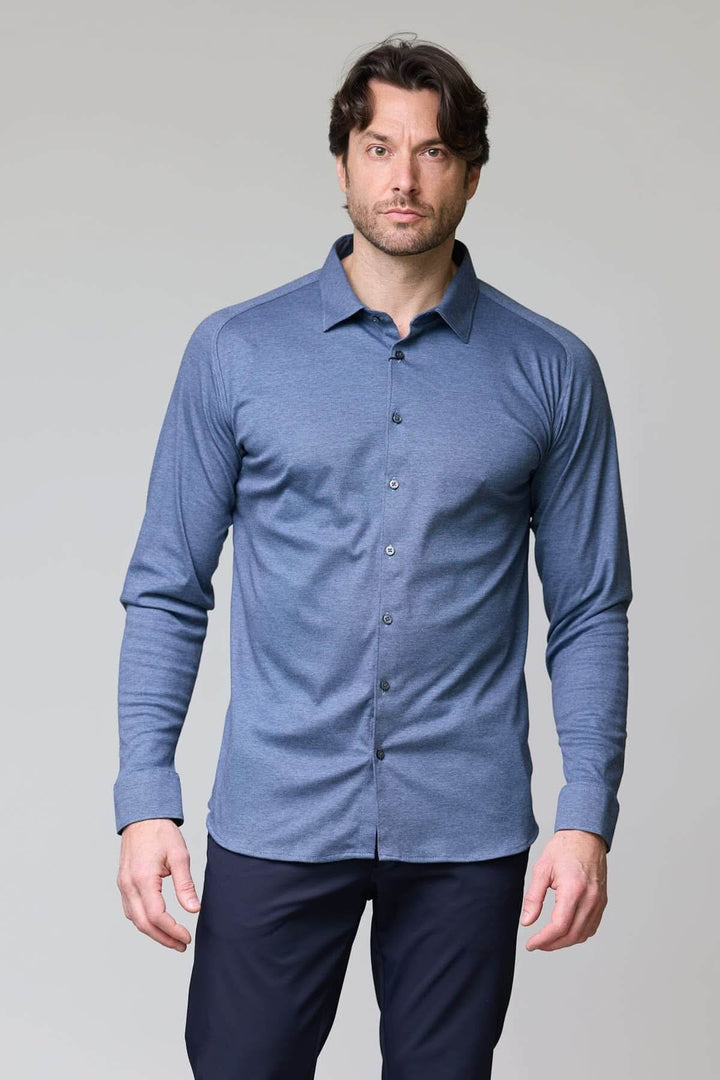 Homme portant une chemise en jersey extensible bleue à manches longues et coupe ajustée, idéale pour le travail ou les loisirs.