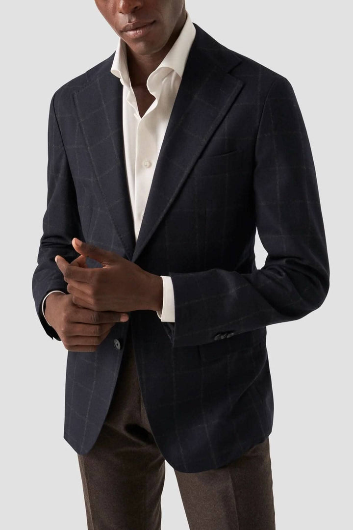 Veste en laine à carreaux, col classique, portée avec une chemise blanche, look élégant et soigné.