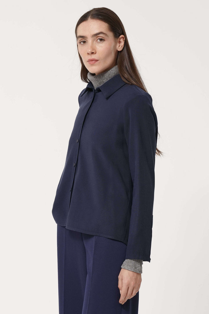 Femme portant une chemise fluide élégante avec col classique et coupe ample, idéale pour un look de bureau chic et minimaliste.