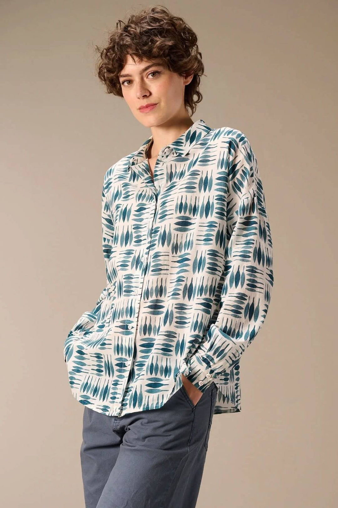 Chemise imprimée à manches longues avec imprimé graphique et matière fluide, portée avec un pantalon pour un look moderne et polyvalent.