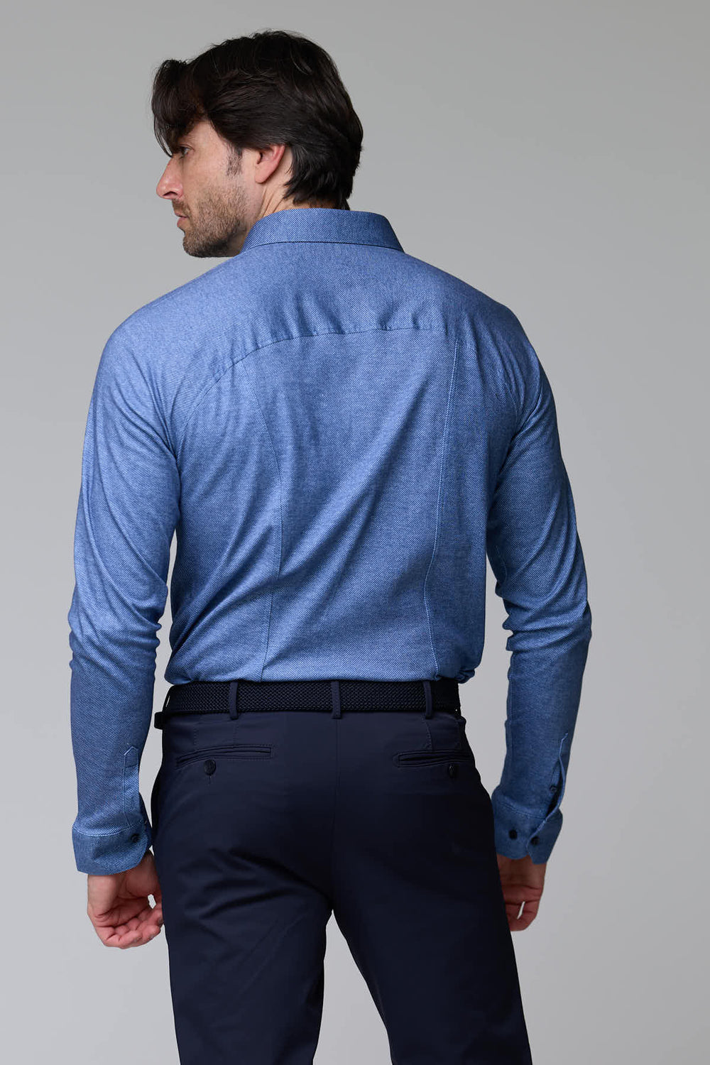 Dos d'un homme portant une chemise jersey texturé bleue, manches longues et col structuré, style moderne et ajusté.