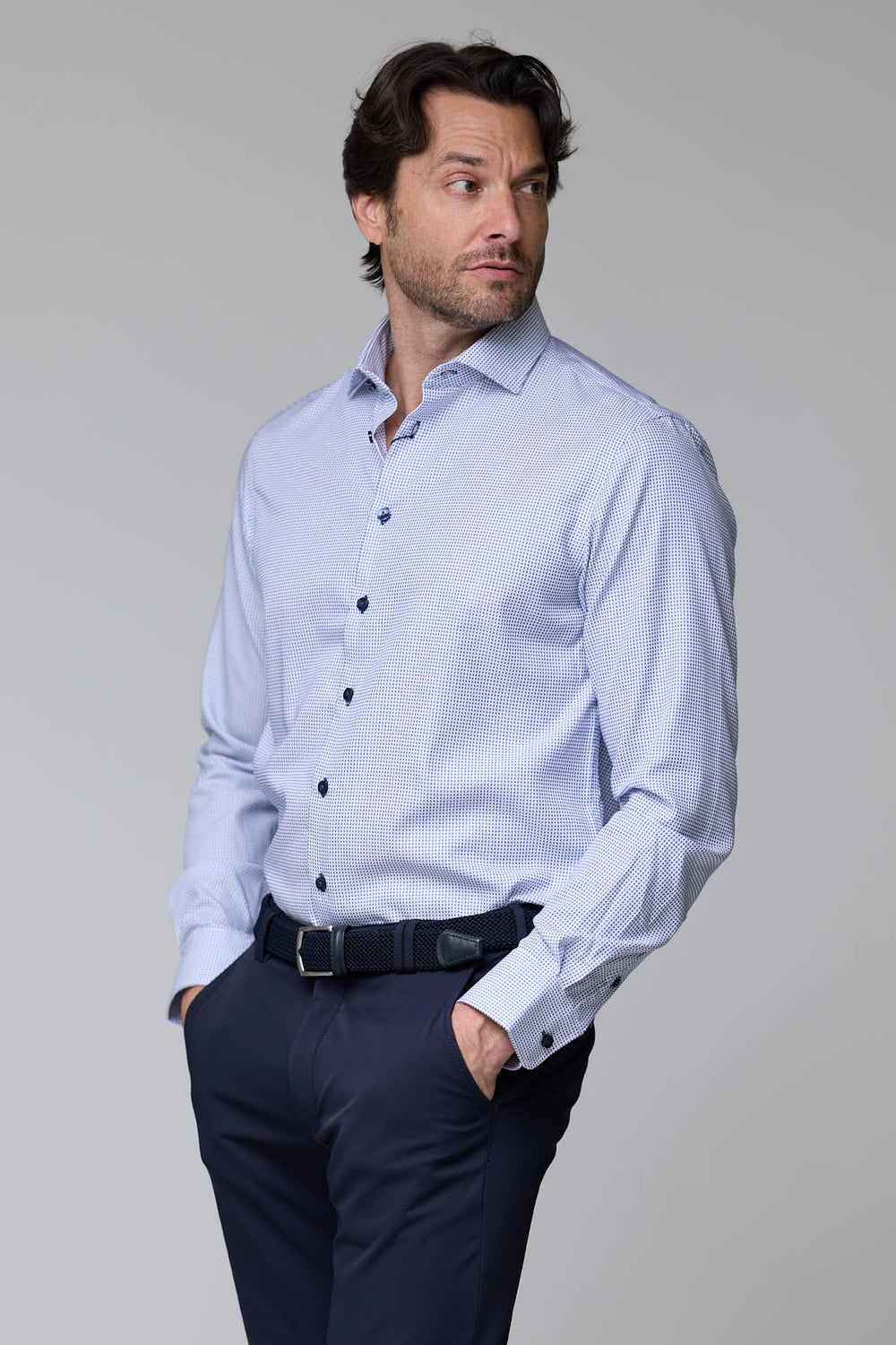 Homme portant une chemise à motif géométrique avec manches longues et boutons contrastants pour un look élégant.