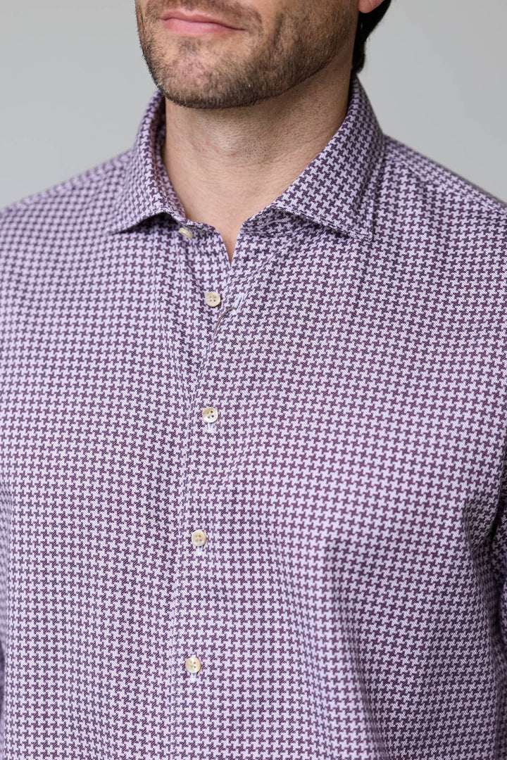 Homme portant une chemise à motif géométrique ajustée aux manches longues et col classique semi-rigide, style moderne élégant.